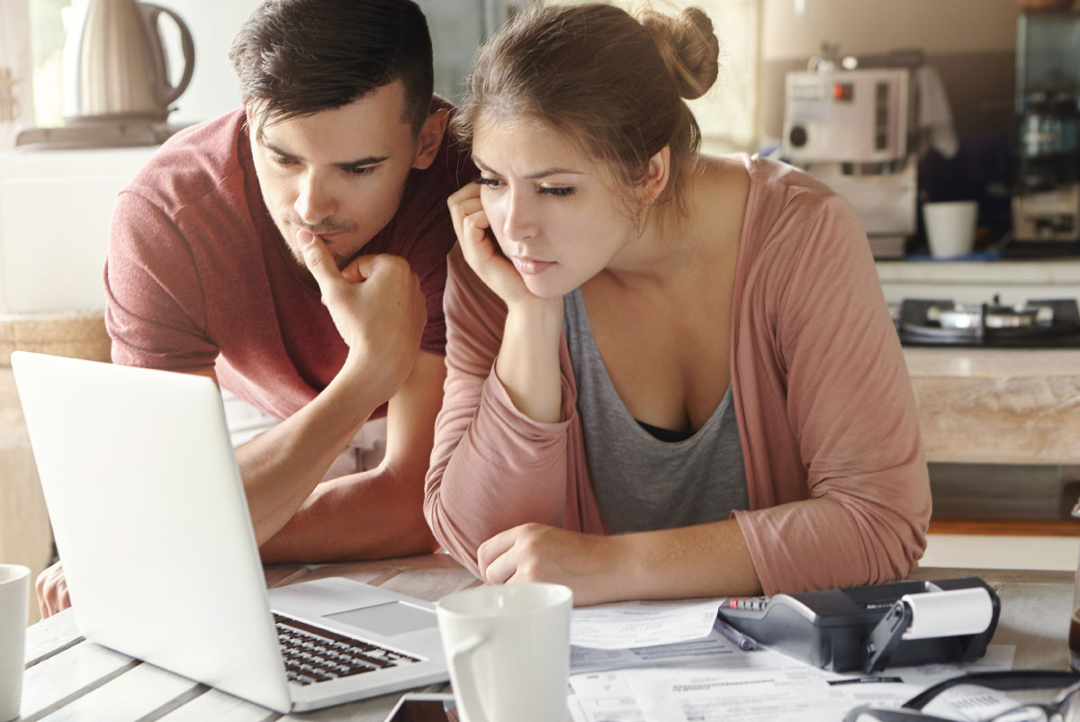 photo of a couple reading about how to get out of debt on a computer